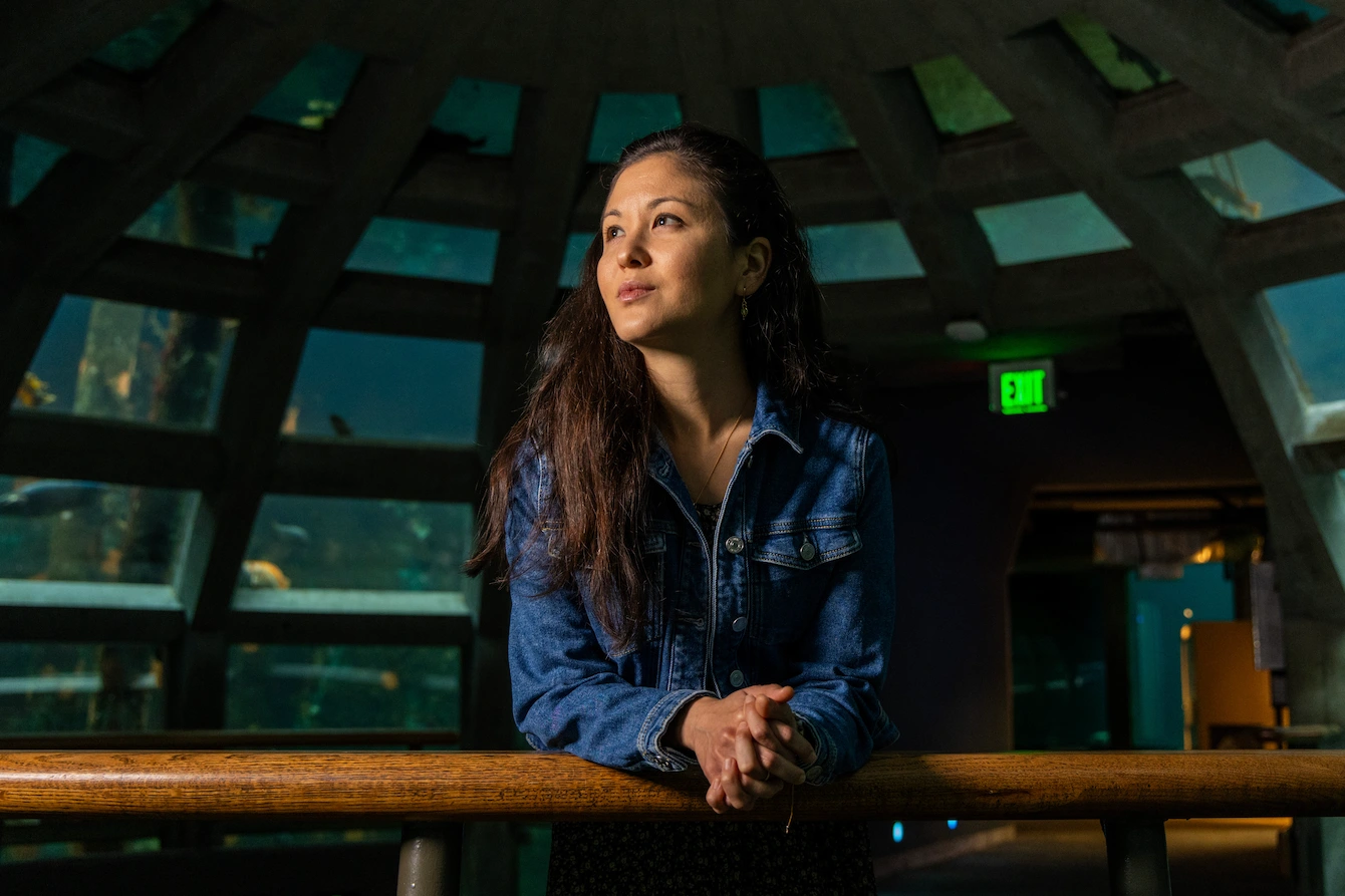 Christine Froschl, a woman with long, dark hair and wearing a jean jacket, standing in the Underwater Dome habitat.