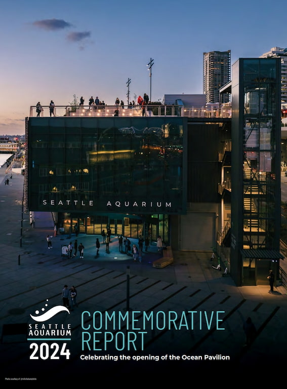 The exterior of the Ocean Pavilion at dusk. The Seattle Aquarium logo and the phrase "2024 Commemorative Report" are in the bottom left corner.